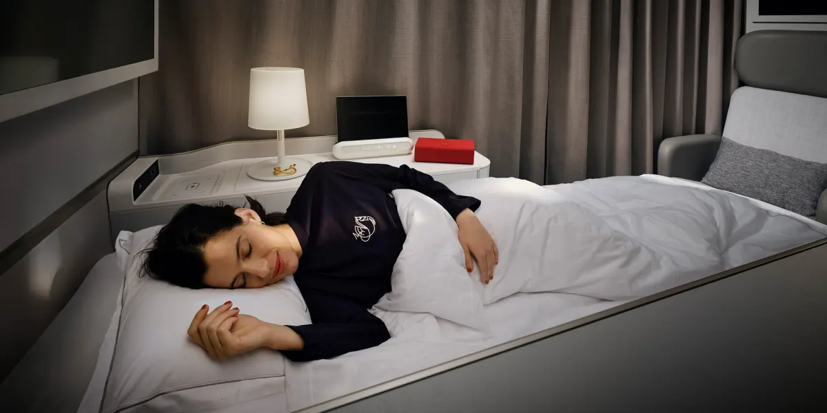 Lit plat dans la nouvelle suite La Première avec couette, oreiller et lampe de chevet